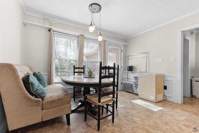 dining area featuring light tile patterned floors, a wainscoted wall, and crown molding