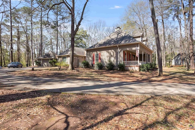 view of front of property with driveway, covered porch, and a chimney