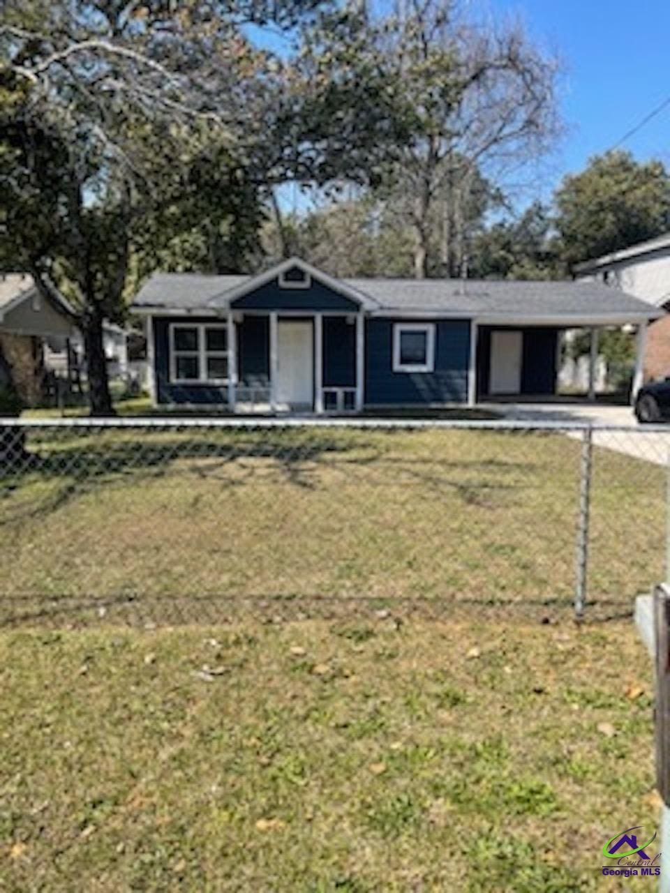 view of front of home with a carport, driveway, a front yard, and fence