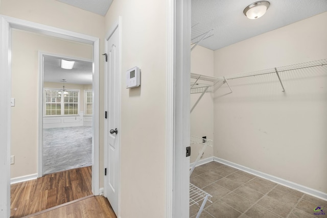 laundry room featuring a textured ceiling, baseboards, and wood finished floors