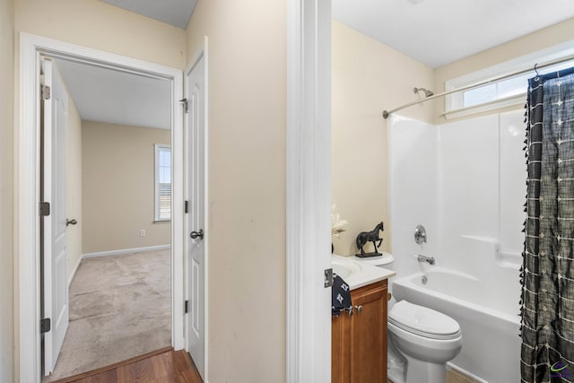 bathroom featuring baseboards, toilet, shower / tub combo, wood finished floors, and vanity