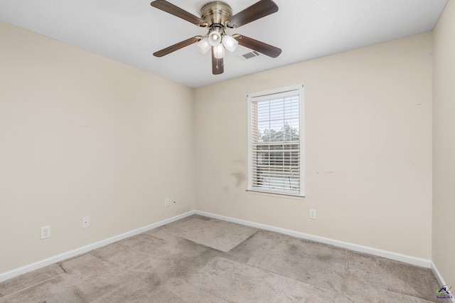 carpeted spare room with visible vents, baseboards, and ceiling fan