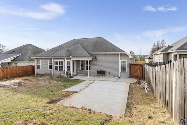 back of house featuring roof with shingles, a yard, a fenced backyard, a patio area, and a gate