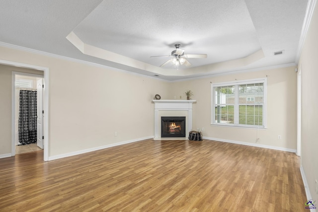 unfurnished living room with light wood-type flooring, visible vents, and a raised ceiling