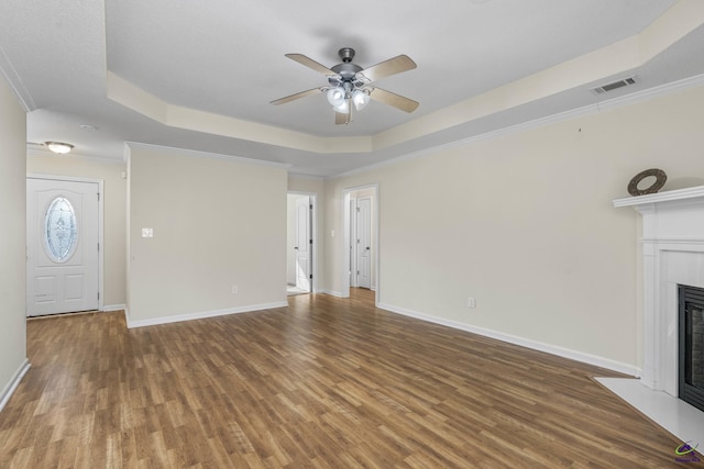 unfurnished living room with a fireplace with flush hearth, baseboards, a tray ceiling, and wood finished floors