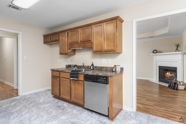 kitchen featuring stainless steel dishwasher, dark countertops, and brown cabinets