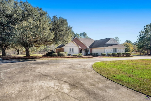 view of front of home with curved driveway and a front lawn