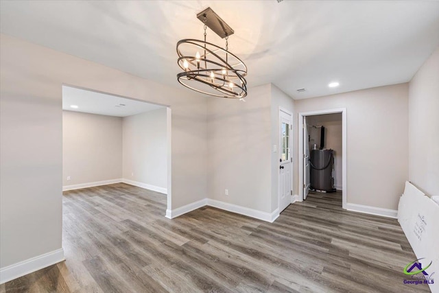 unfurnished dining area featuring a notable chandelier, recessed lighting, baseboards, and wood finished floors