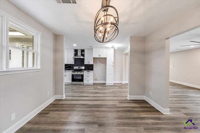 unfurnished dining area with visible vents, an inviting chandelier, baseboards, and wood finished floors