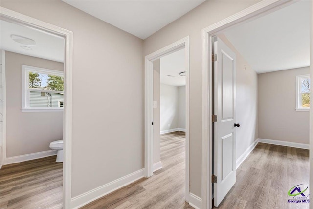 corridor with light wood-style flooring and baseboards