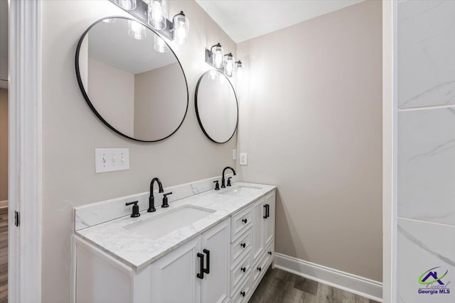 full bathroom featuring double vanity, wood finished floors, baseboards, and a sink