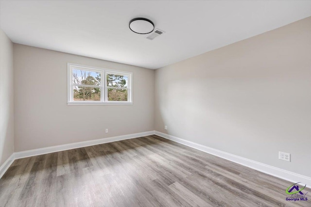 empty room with visible vents, baseboards, and wood finished floors