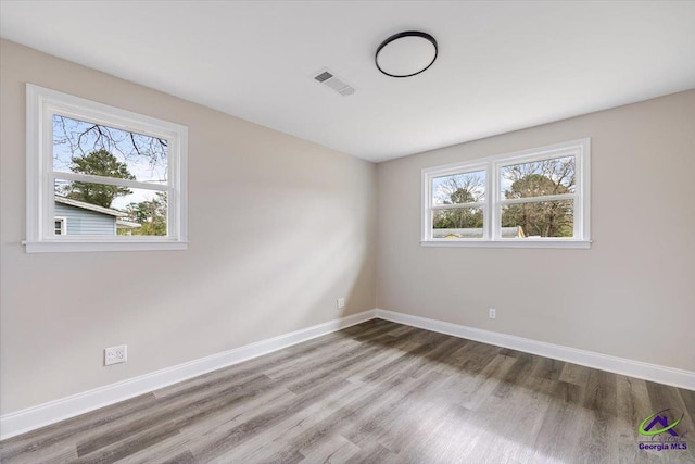 empty room featuring visible vents, baseboards, and wood finished floors