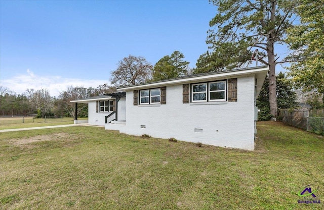 view of front of property featuring crawl space, brick siding, a front lawn, and fence