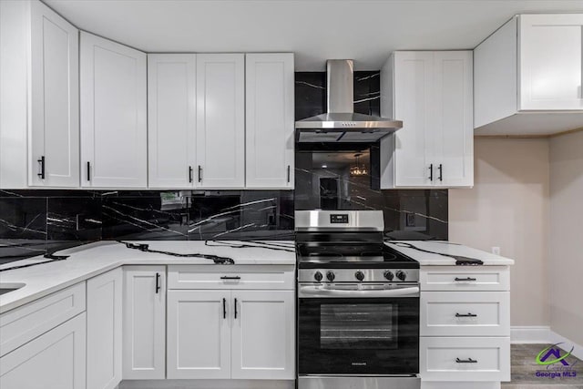 kitchen featuring electric range, backsplash, white cabinetry, and wall chimney range hood