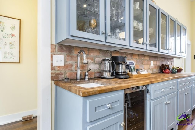 bar with a sink, wine cooler, decorative backsplash, baseboards, and a dry bar