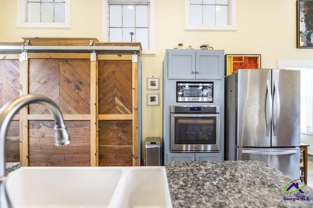 kitchen featuring a sink, appliances with stainless steel finishes, and dark stone countertops