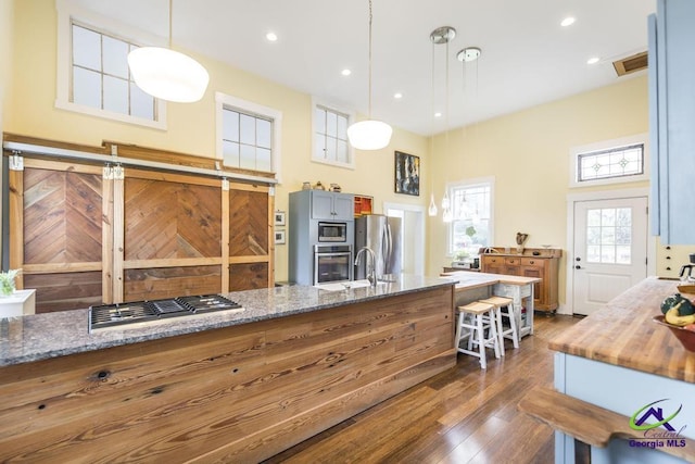 kitchen featuring visible vents, dark wood finished floors, light stone counters, appliances with stainless steel finishes, and a high ceiling