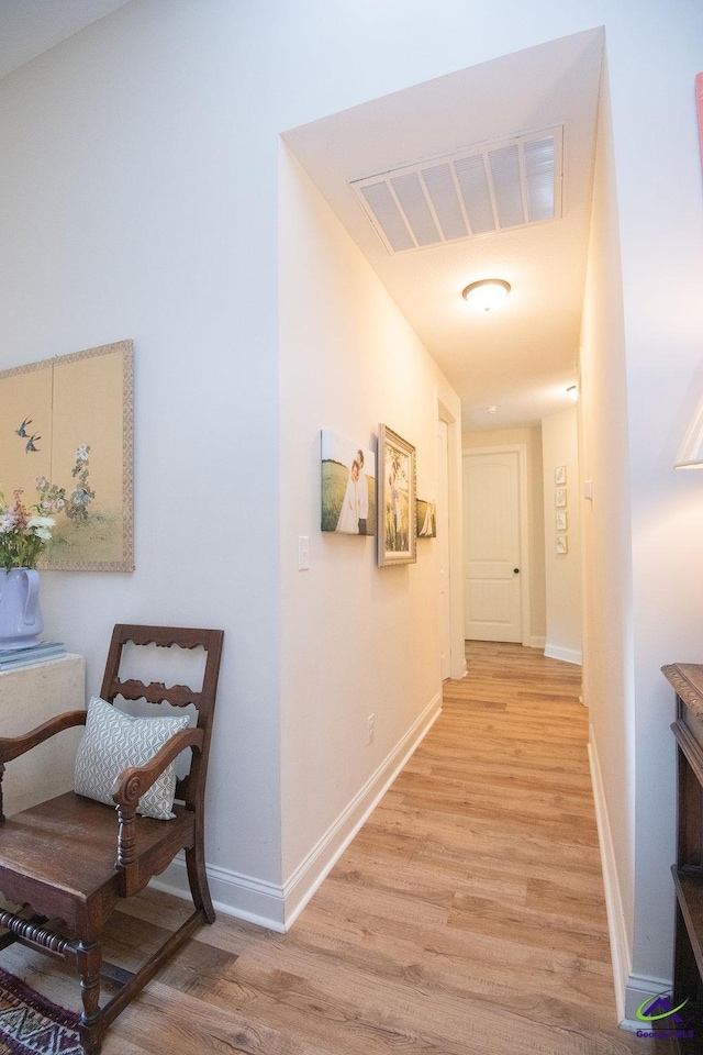 hall featuring visible vents, baseboards, and light wood-style flooring