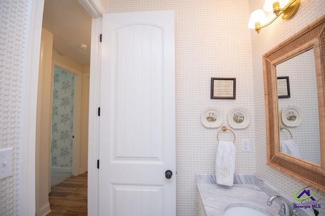 bathroom featuring wallpapered walls, vanity, and wood finished floors