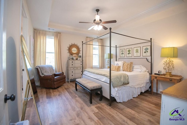 bedroom featuring multiple windows, wood finished floors, and crown molding