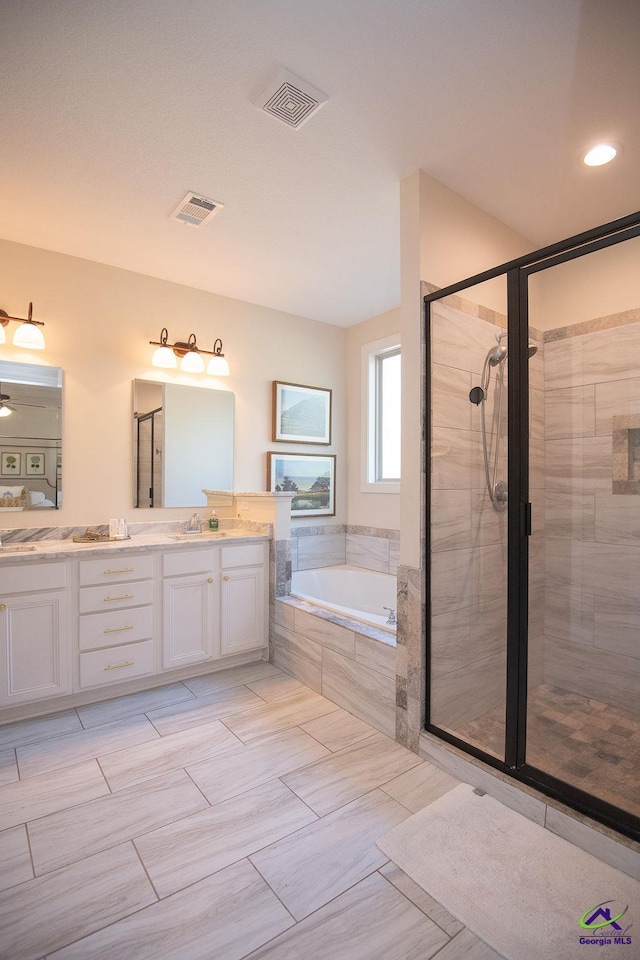 bathroom featuring visible vents, a garden tub, double vanity, a stall shower, and a sink