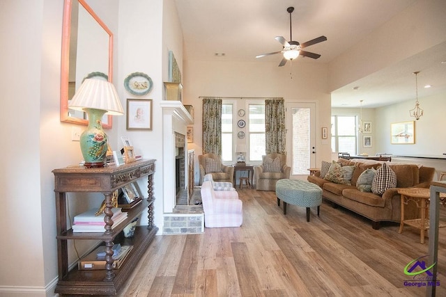 living area with ceiling fan, wood finished floors, and a fireplace