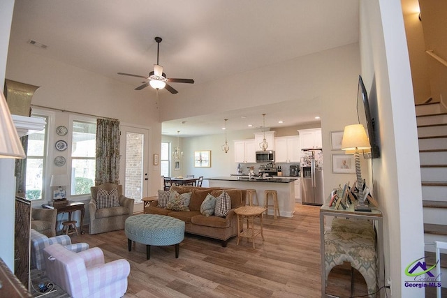 living room featuring visible vents, ceiling fan, stairs, and light wood-style floors