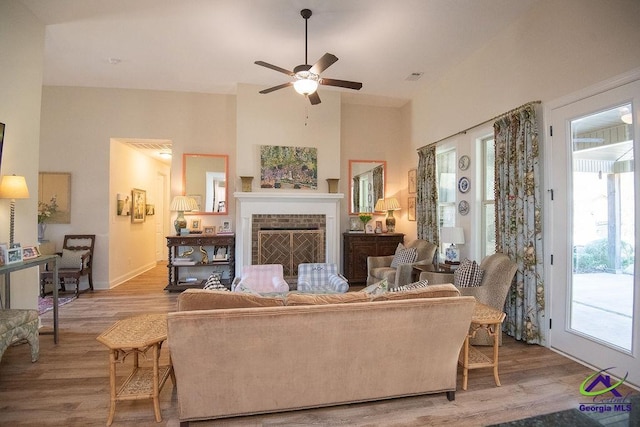 living area featuring visible vents, a brick fireplace, wood finished floors, and a high ceiling