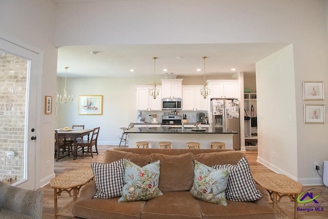 living area featuring an inviting chandelier, recessed lighting, baseboards, and light wood-type flooring