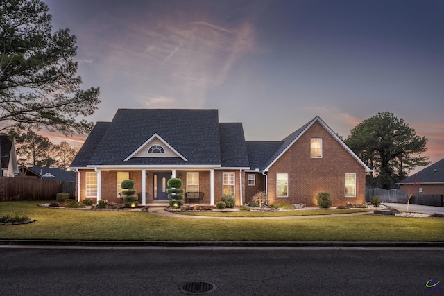 view of front of property with a front lawn, fence, and brick siding