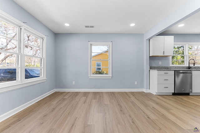 kitchen featuring visible vents, light wood-style flooring, white cabinetry, baseboards, and dishwasher