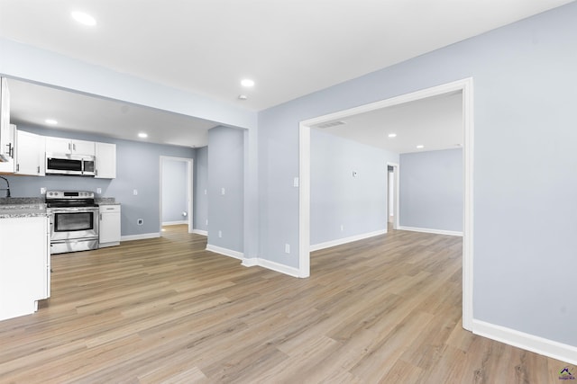 kitchen featuring white cabinets, baseboards, light wood finished floors, and stainless steel appliances