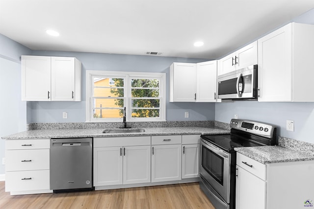 kitchen featuring visible vents, white cabinets, stainless steel appliances, and a sink