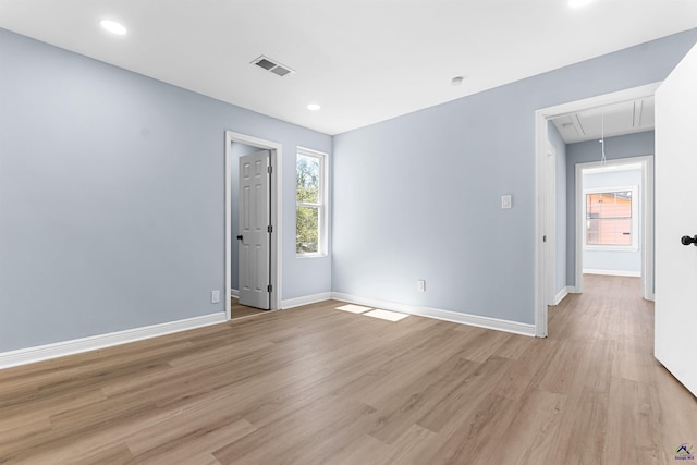 empty room featuring visible vents, plenty of natural light, light wood-style floors, and attic access