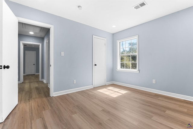 unfurnished bedroom with visible vents, baseboards, attic access, light wood-style floors, and a closet