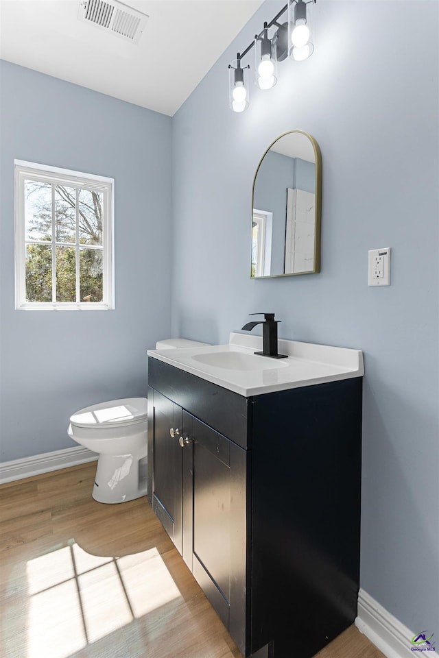 bathroom featuring vanity, wood finished floors, visible vents, baseboards, and toilet