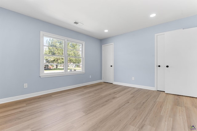 unfurnished bedroom featuring light wood finished floors, visible vents, two closets, baseboards, and recessed lighting