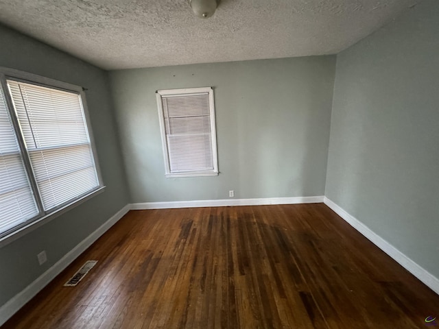 spare room with baseboards, visible vents, wood-type flooring, and a textured ceiling