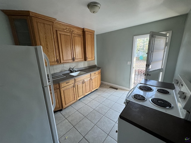 kitchen with dark countertops, visible vents, light tile patterned floors, white appliances, and a sink