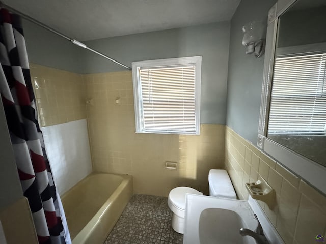 full bathroom with a wealth of natural light, toilet, tile walls, and shower / tub combo