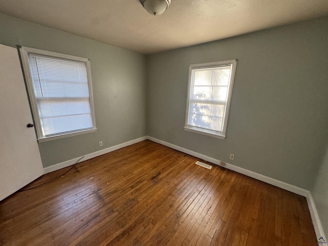 spare room featuring visible vents, wood-type flooring, and baseboards