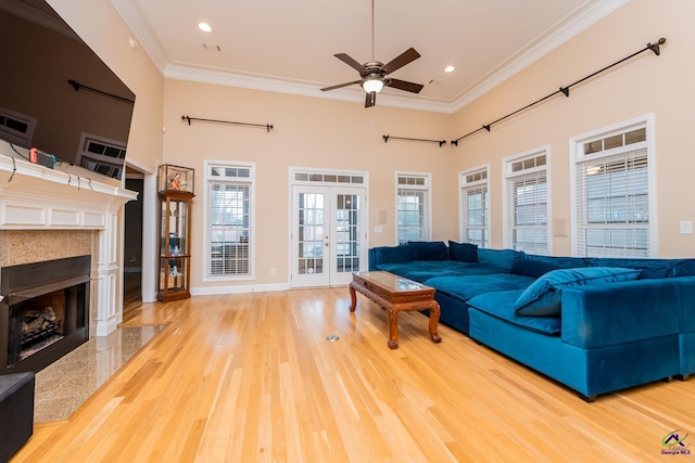 living room featuring a premium fireplace, ornamental molding, french doors, wood finished floors, and a ceiling fan