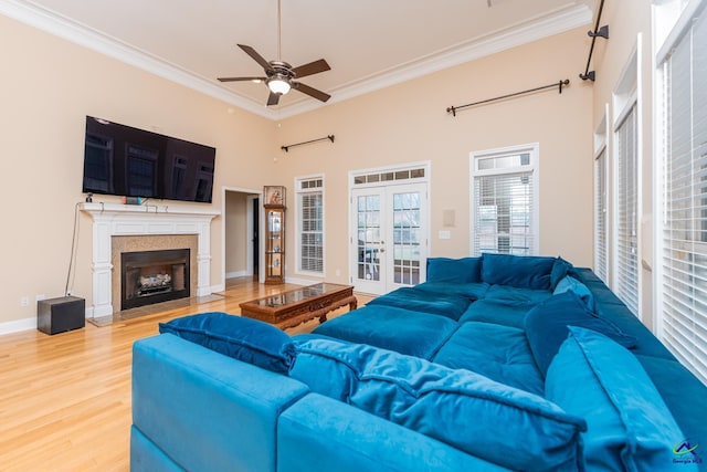 living area featuring a ceiling fan, wood finished floors, french doors, crown molding, and baseboards