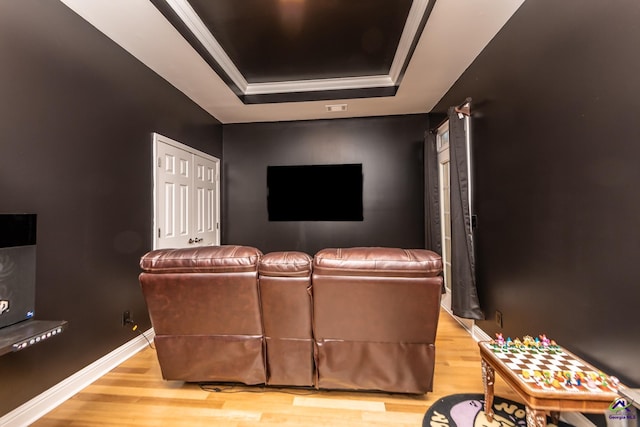 cinema featuring a tray ceiling, wood finished floors, and baseboards