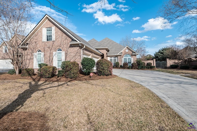 view of front of property with brick siding, a front lawn, fence, concrete driveway, and an attached garage