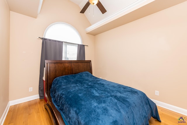 bedroom featuring wood finished floors, a ceiling fan, baseboards, and vaulted ceiling