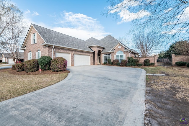 view of front facade featuring brick siding, an attached garage, concrete driveway, and fence