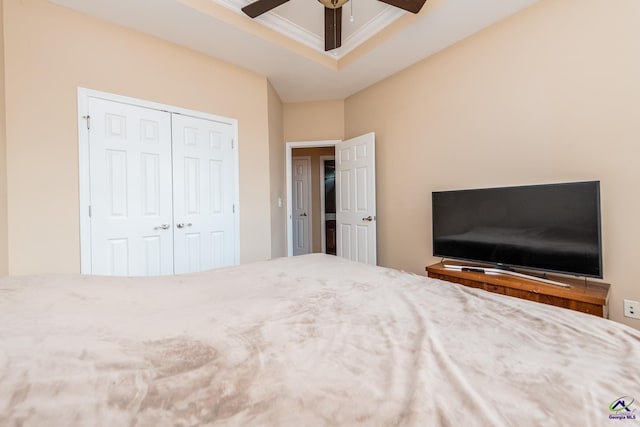 unfurnished bedroom with a closet, a raised ceiling, a ceiling fan, and ornamental molding