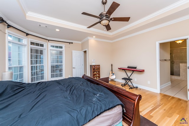 bedroom featuring a tray ceiling, wood finished floors, crown molding, and visible vents